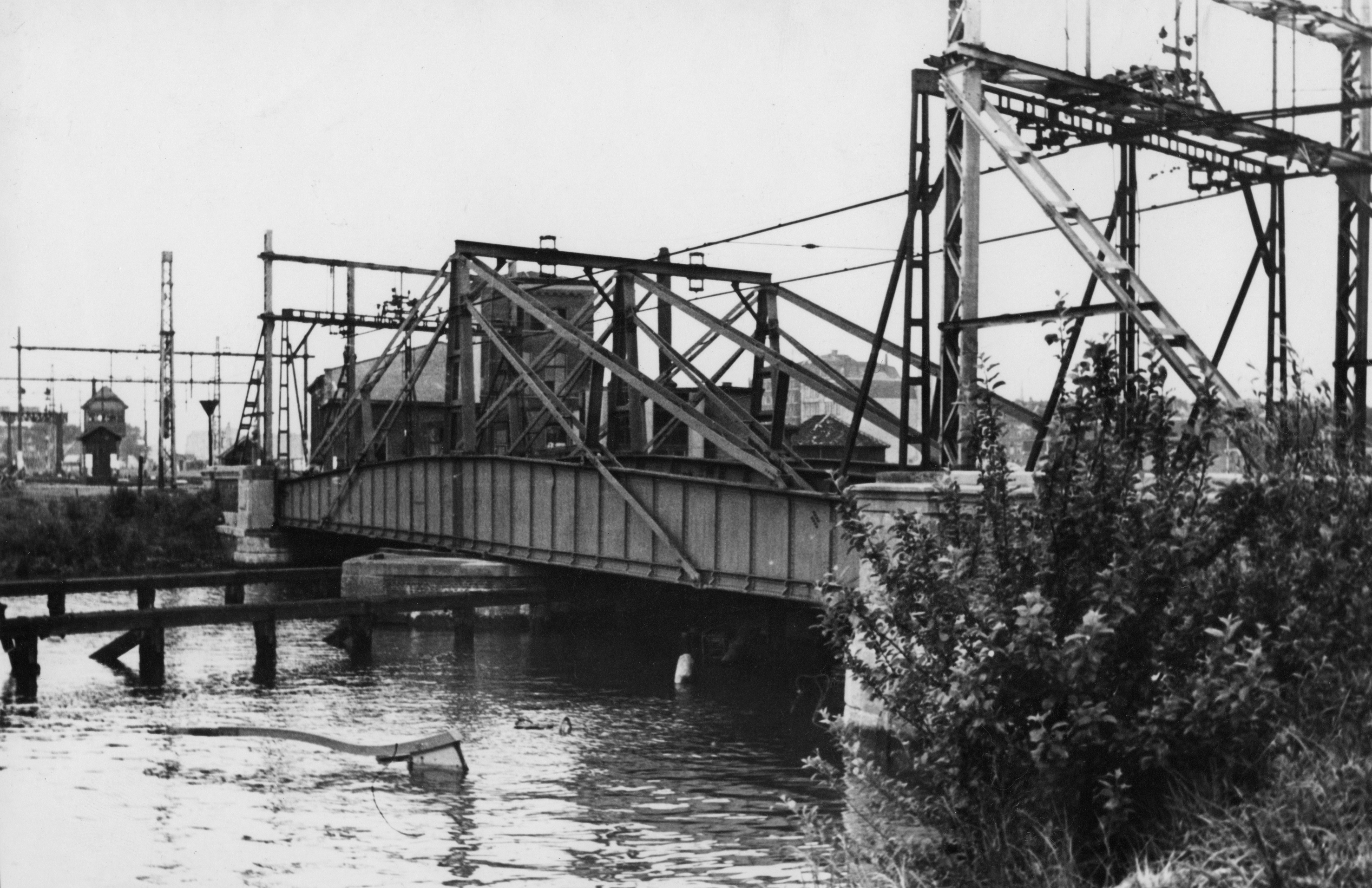 Spoorbrug bij Rotterdam met in het water gezonken binnenvaartschip, ter versperring van de haven